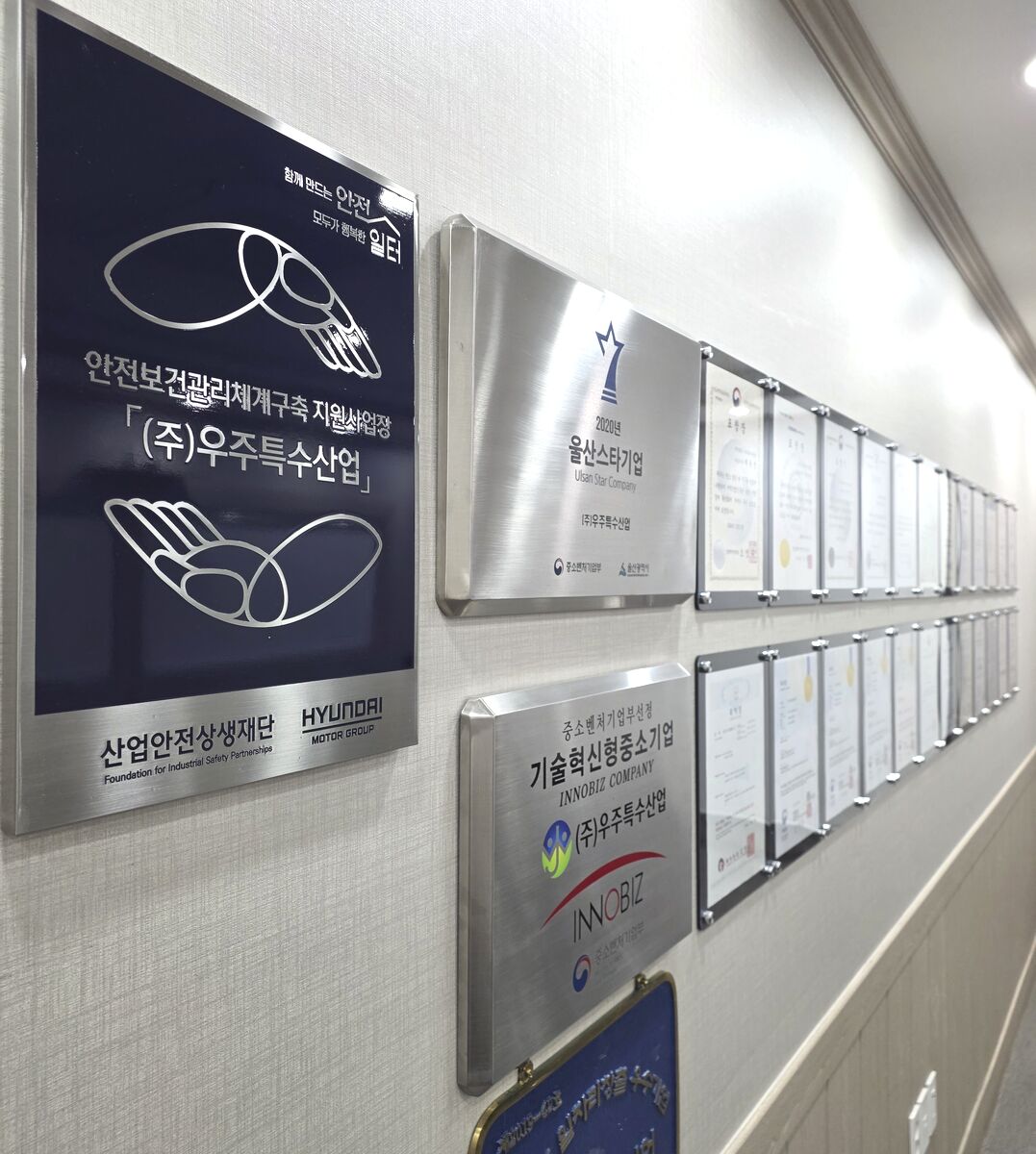 (주)우주특수산업 인증 현황판 — 현대자동차그룹 안전보건 지원사업장, 울산스타기업, 기술혁신형 중소기업(Inno-Biz) 등 인증·표창 게시